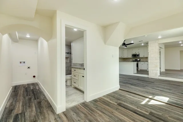 a view of a hallway with wooden floor and a bathroom
