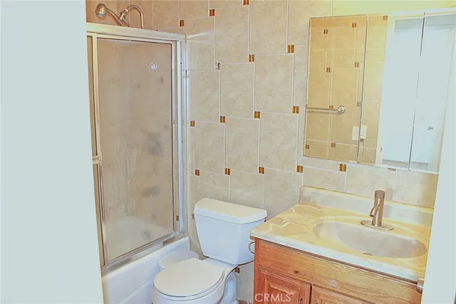 a bathroom with a granite countertop sink a toilet and shower