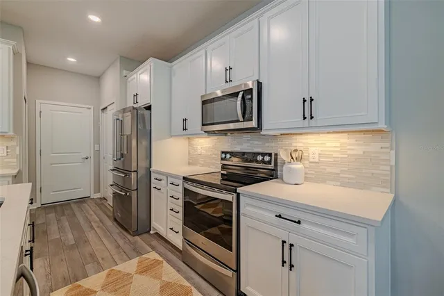 a kitchen with stainless steel appliances white cabinets and a stove top oven