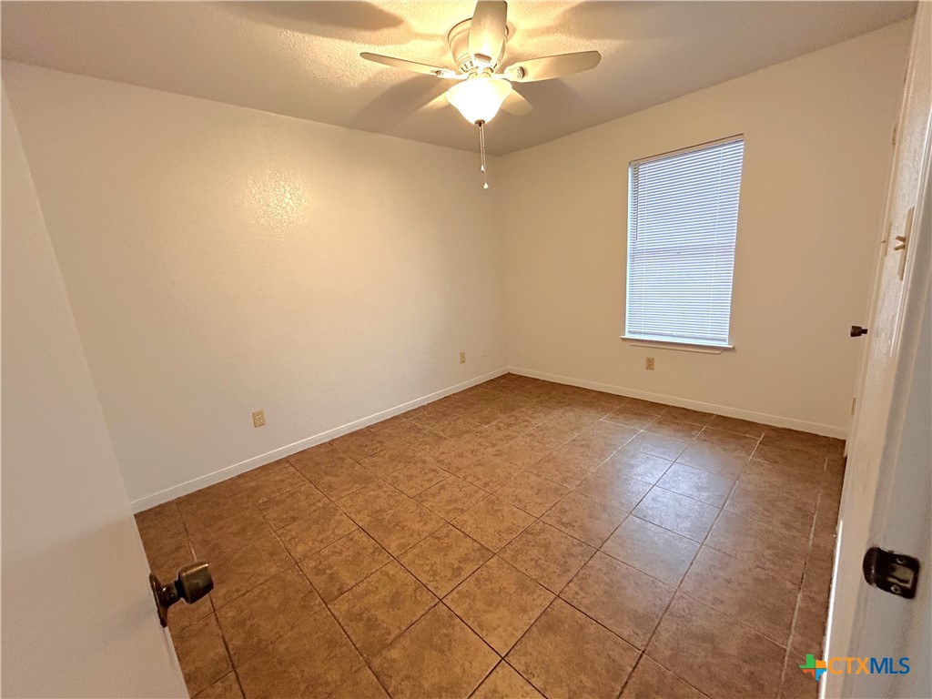 10411 Chaparral Road Killeen, TX 76548 - Photo 11 of 13 an empty room with a chandelier fan and windows