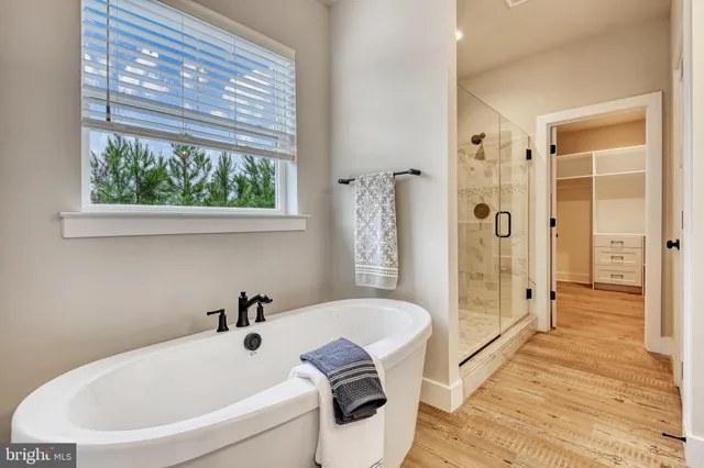 a bathroom with a tub a sink and a large mirror next to a window