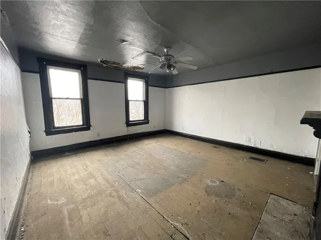 an empty room with windows and ceiling fan