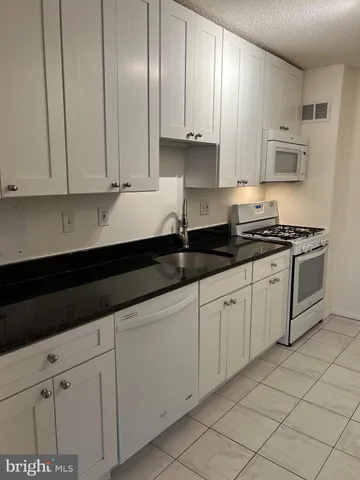 a kitchen with stainless steel appliances granite countertop white cabinets sink and dishwasher