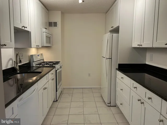 a kitchen with granite countertop white cabinets and stainless steel appliances
