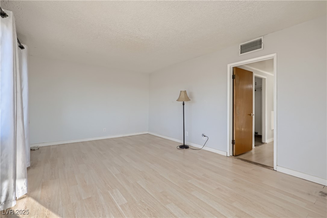 103 West Victory Road Henderson, NV 89015 - Photo 8 of 28 Spare room featuring light wood-style floors, a textured ceiling, and baseboards