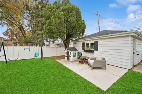 a view of a white house with a yard and sitting area