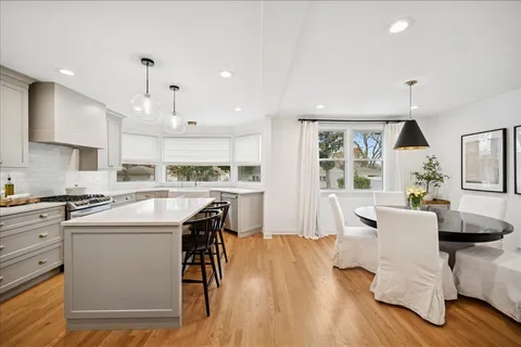 a kitchen with stainless steel appliances granite countertop a stove top oven a sink dishwasher a dining table and chairs with wooden floor