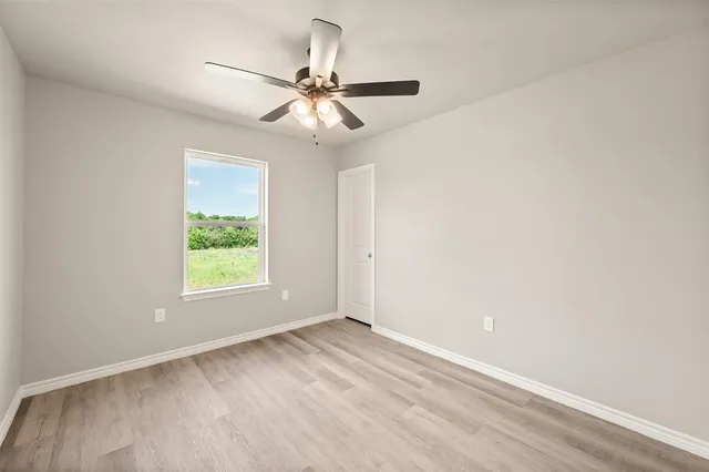 an empty room with a window and a fan