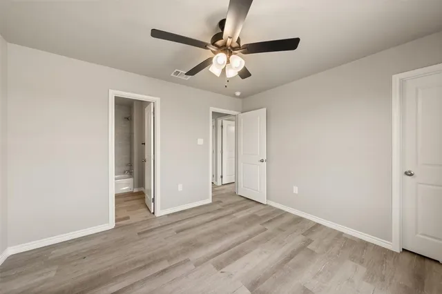 a view of an empty room and chandelier fan