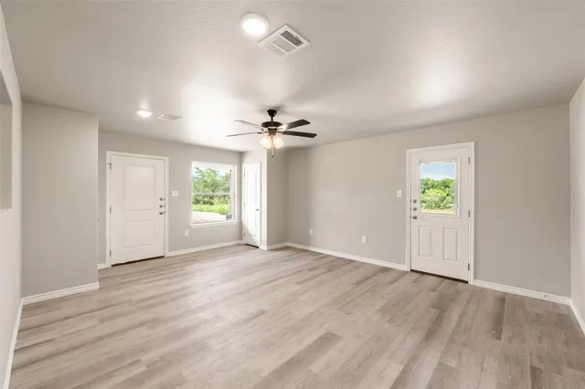 an empty room with wooden floor mirror and windows