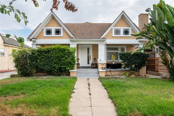 a front view of a house with a yard and potted plants