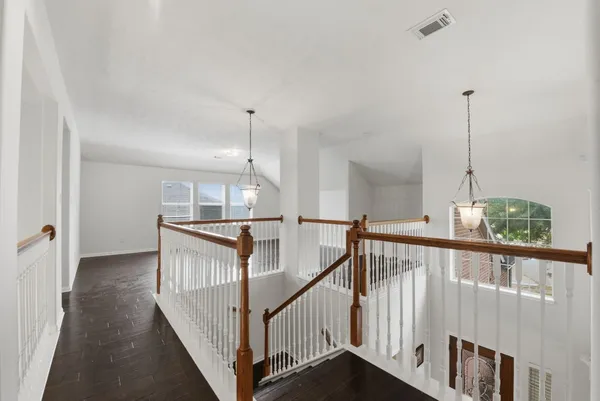 a view of a hallway with wooden floor and windows