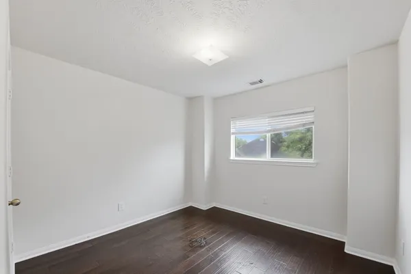 an empty room with wooden floor fan and window