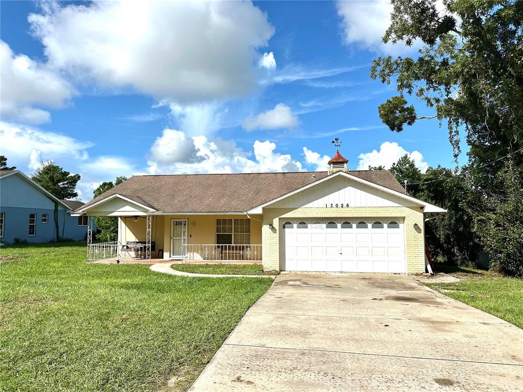 13026 Lawrence Street Spring Hill, FL 34609 - Photo 1 of 1 a front view of a house with a yard and garage