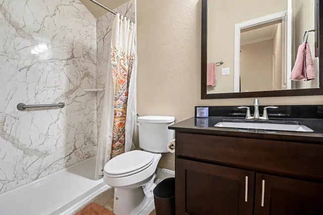 a bathroom with a granite countertop sink toilet and shower