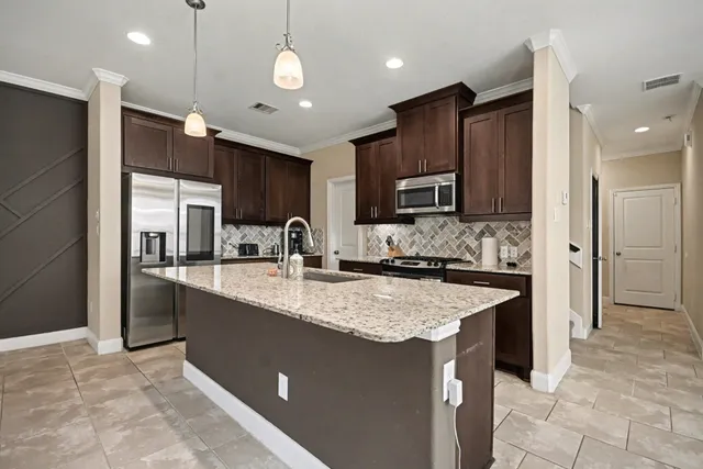 a kitchen with stainless steel appliances granite countertop a sink a stove a refrigerator and a oven