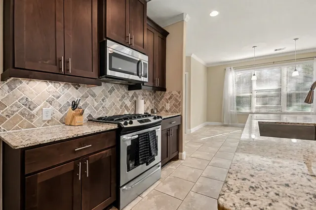 a kitchen with granite countertop a stove a sink and a microwave