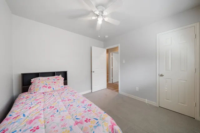 a bedroom with a bed and a chandelier fan