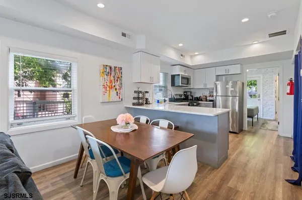 a kitchen with stainless steel appliances granite countertop a refrigerator a sink dishwasher a stove and white countertops with wooden floor