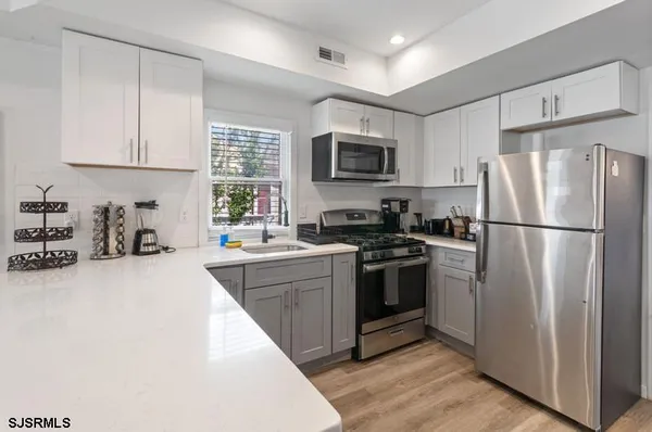 a kitchen with stainless steel appliances granite countertop a sink a stove a microwave and wooden cabinets