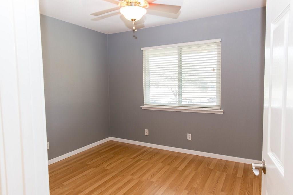 4209 Burnet Road, Unit 206 Austin, TX 78756 - Photo 15 of 20 A well-lit bedroom features hardwood flooring and a functional ceiling fan.