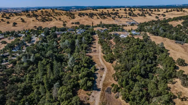 an aerial view of residential house with outdoor space and trees all around