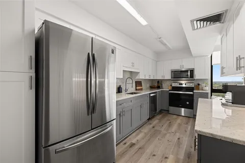 a kitchen with granite countertop white cabinets and stainless steel appliances