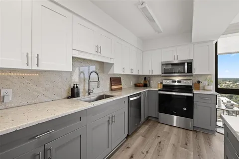 a kitchen with granite countertop a sink a counter top space appliances and cabinets