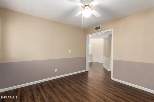 an empty room with wooden floor fan and windows