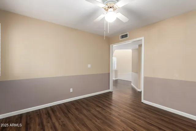 an empty room with wooden floor fan and windows