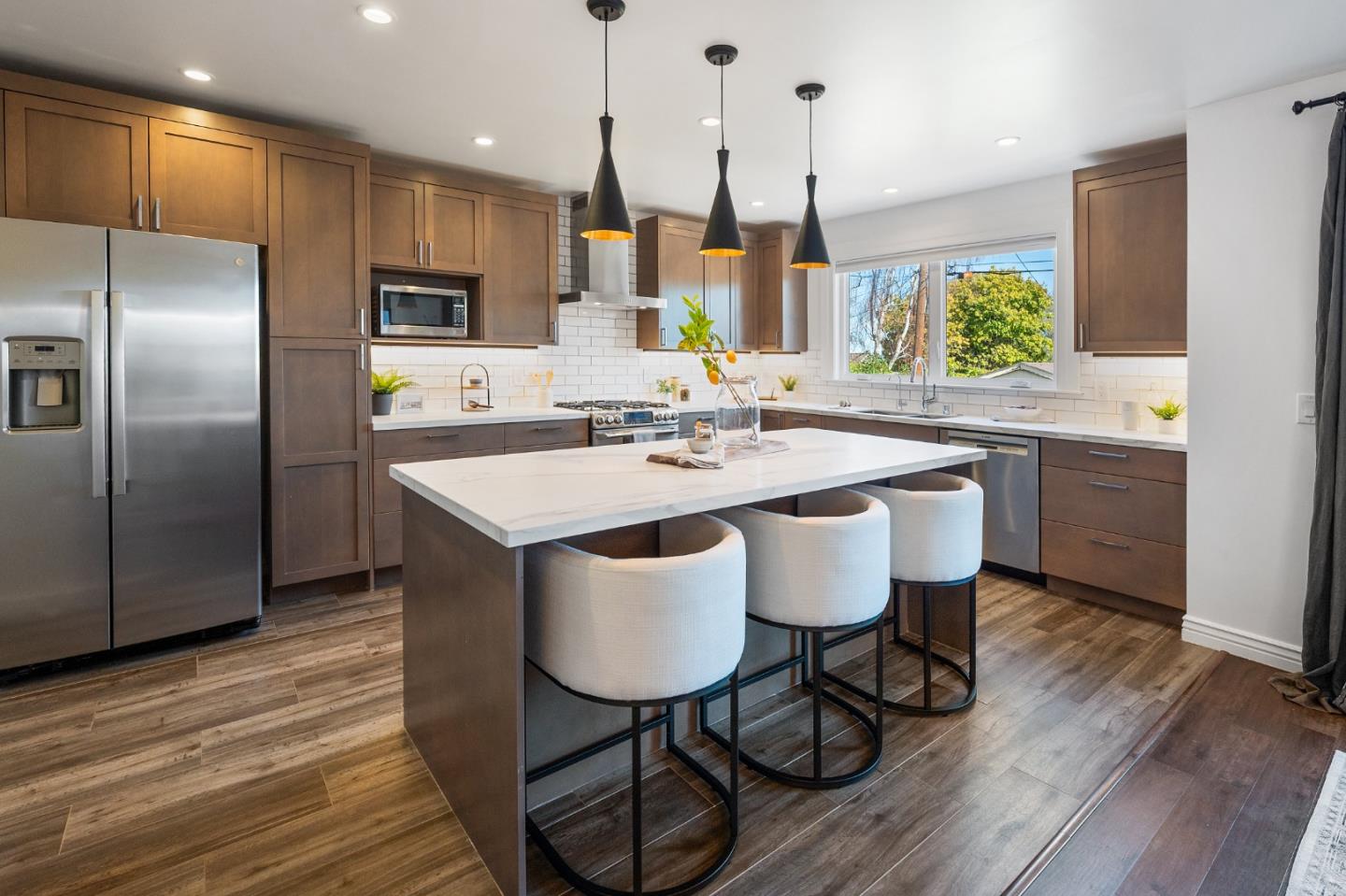 260 Willow Avenue Millbrae, CA 94030 - Photo 14 of 31 a kitchen with stainless steel appliances kitchen island granite countertop a table chairs sink and wooden floor
