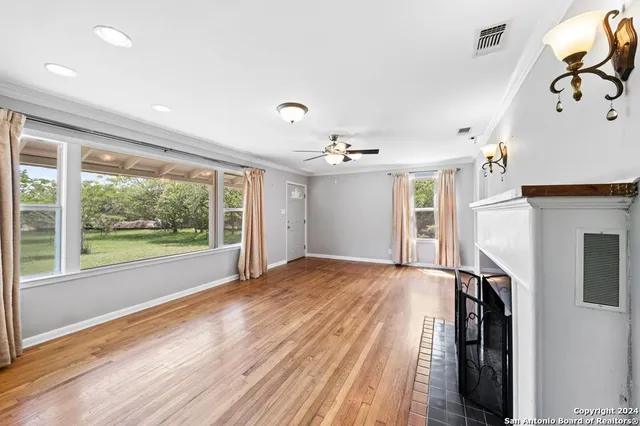 a view of empty room with wooden floor and fan