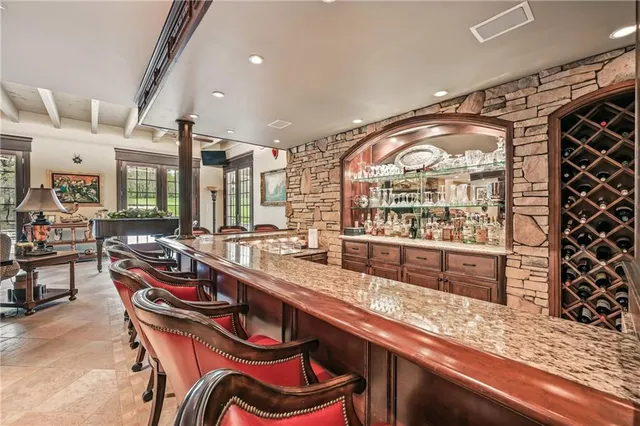 a very nice looking kitchen with granite countertop a stove a sink and dishwasher wooden cabinets with a large mirror