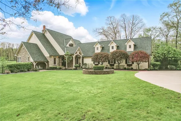 a view of a big house with a big yard and large trees