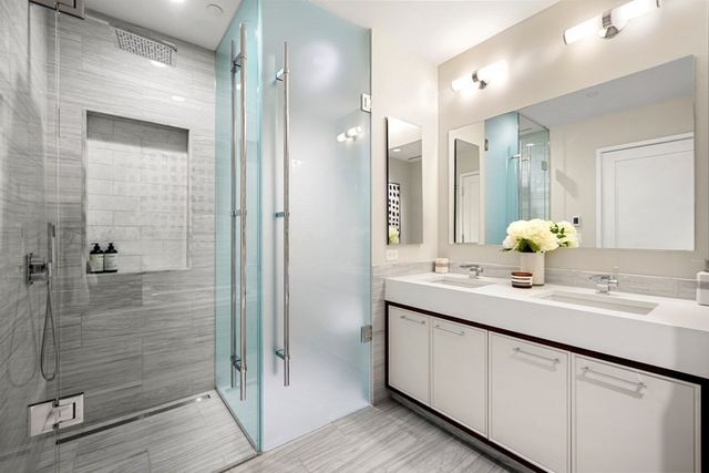 a bathroom with a double vanity sink mirror and shower
