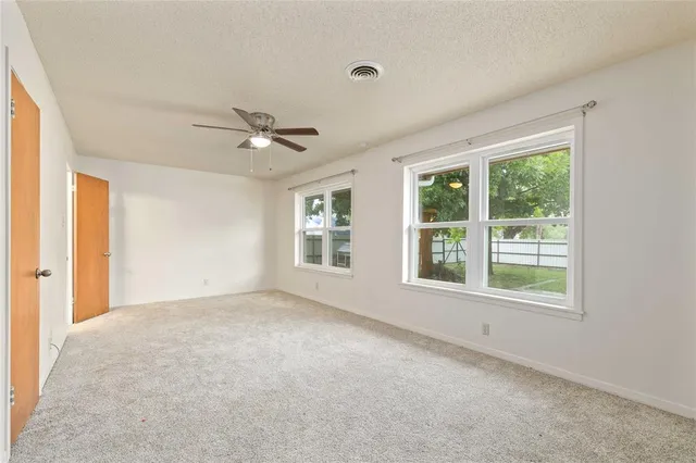 an empty room with a ceiling fan and window