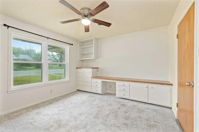 an empty room with windows and fan