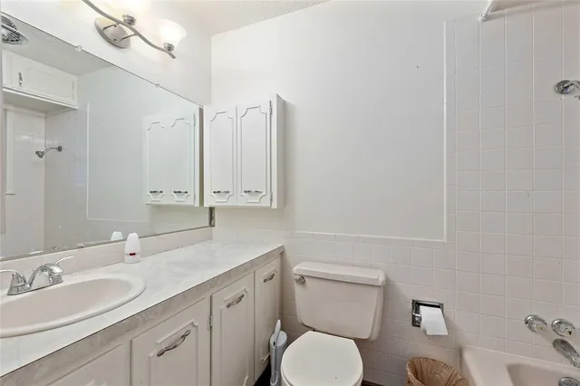 a bathroom with a granite countertop toilet sink and mirror