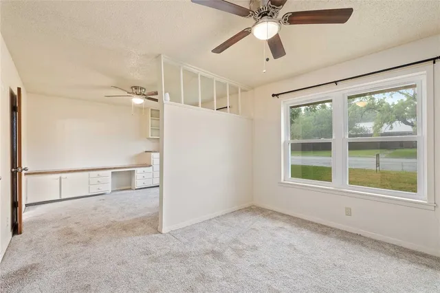an empty room with chandelier fan and windows