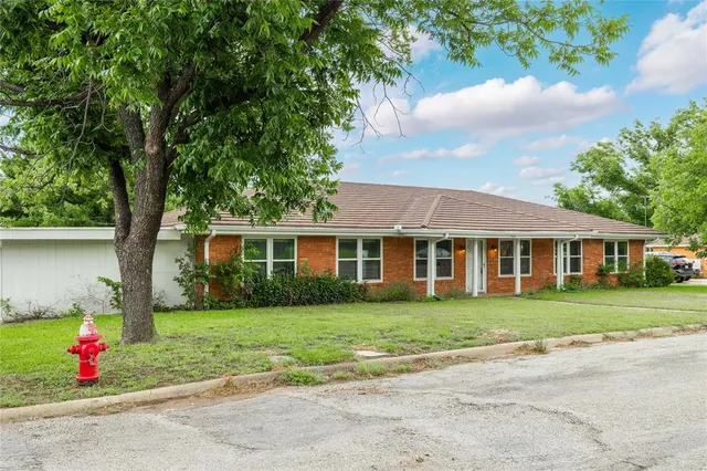 a front view of a house with a yard and trees