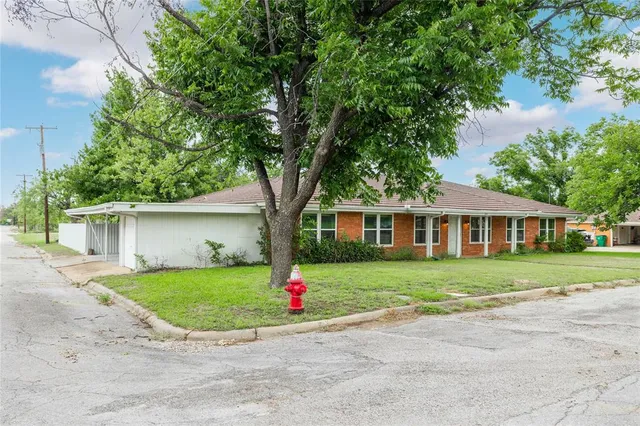 a front view of a house with a garden and trees