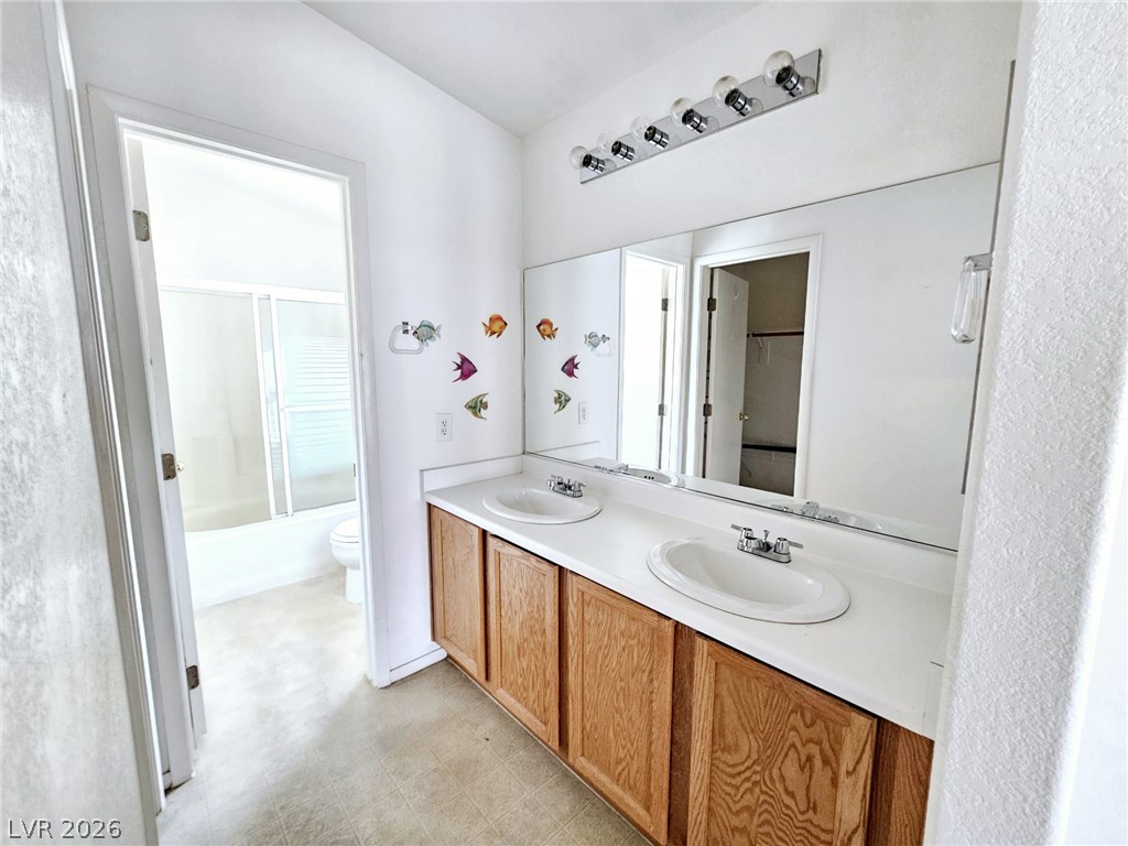 1663 Lefty Garcia Way Henderson, NV 89002 - Photo 3 of 31 Double vanity sinks and bright lighting adorn this functional bathroom space.