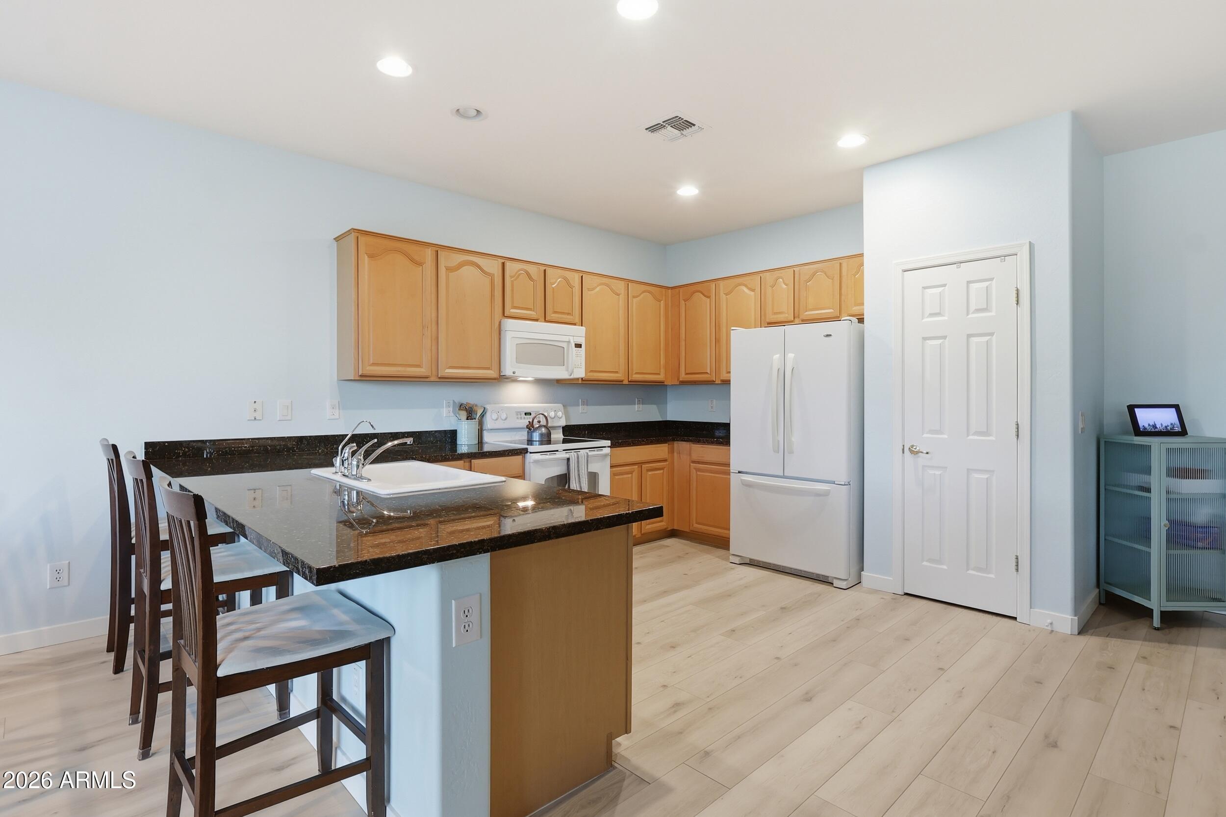 20357 North Lemon Drop Drive Maricopa, AZ 85138 - Photo 4 of 39 a kitchen with a sink a kitchen island and stainless steel appliances