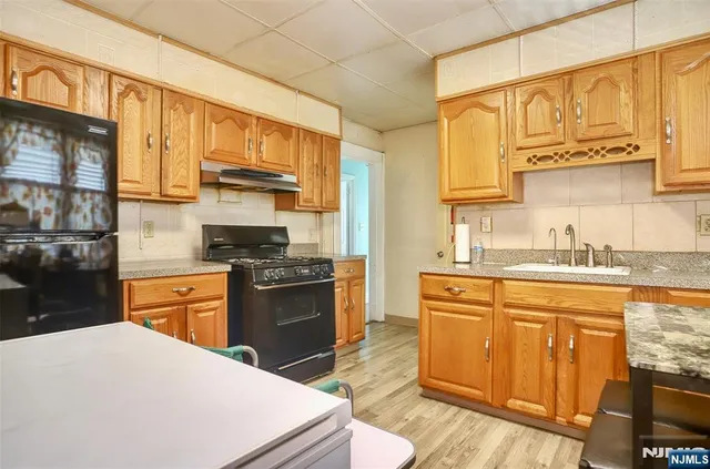 a kitchen with stainless steel appliances granite countertop a stove a sink dishwasher and a refrigerator with wooden cabinets