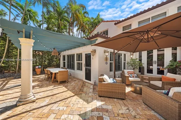 a view of a patio with couches table and chairs under an umbrella