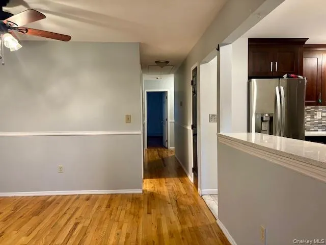 a view of a hallway with wooden floor and a refrigerator