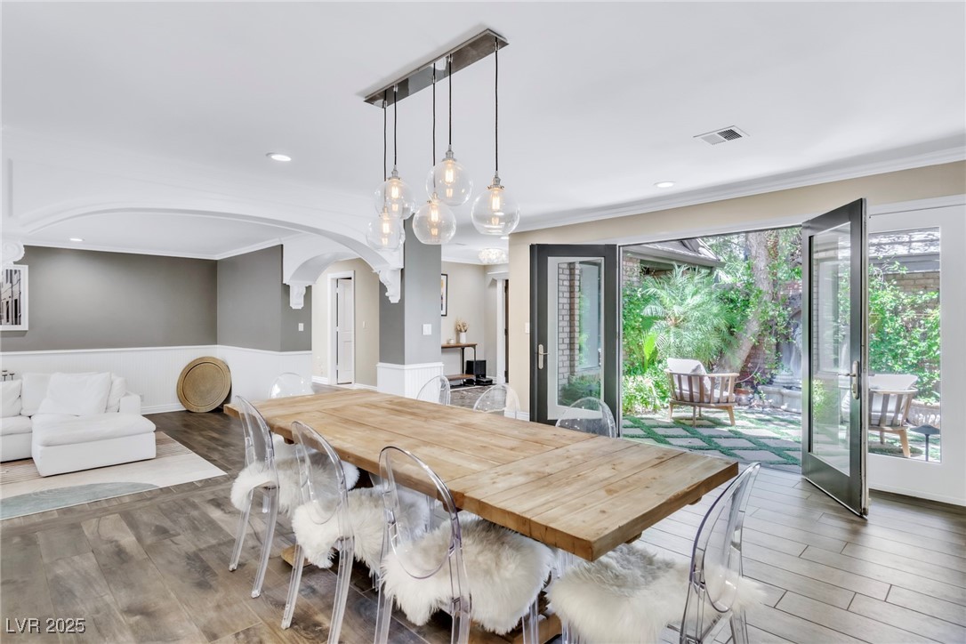 108 Quail Run Road Henderson, NV 89014 - Photo 21 of 50 Dining room featuring wood finished floors, crown molding, arched walkways, recessed lighting, and a wainscoted wall