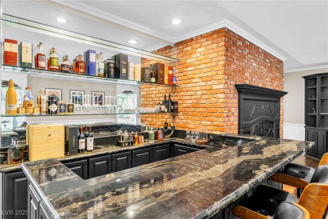 108 Quail Run Road Henderson, NV 89014 - Photo 8 of 50 Indoor wet bar with crown molding, dark stone counters, and dark cabinetry