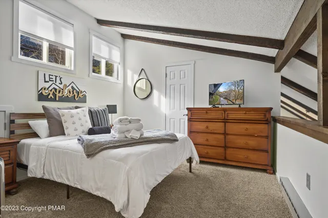 a bedroom with a bed and a lamp on dresser