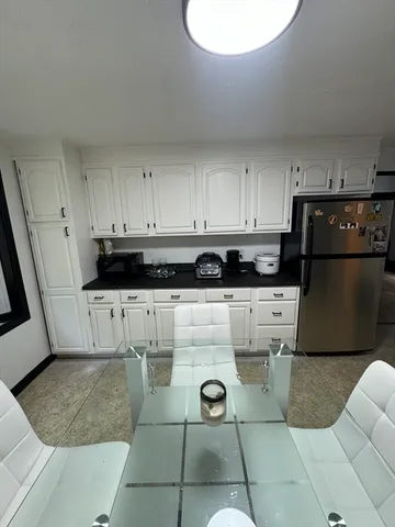 a kitchen with stainless steel appliances granite countertop a refrigerator a stove a sink and white cabinets